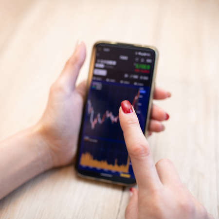 Women's hands investing in smartphonesの写真素材