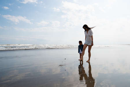 Mother and child walking on the beachの写真素材