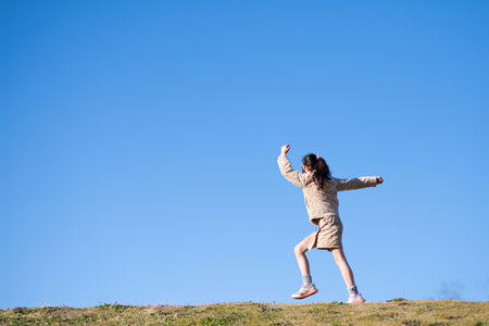 A child walking vigorously under the blue skyの写真素材