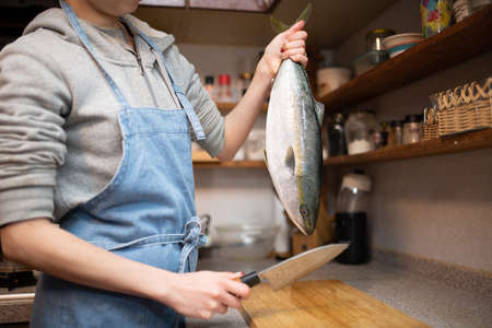 Female cooking raw fish in the kitchenの写真素材