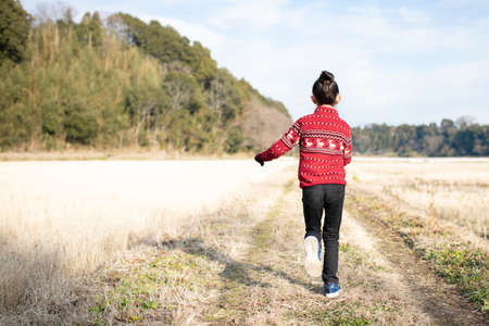 A child walking along a rice field in winterの写真素材