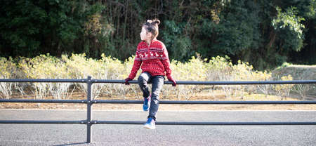 Bored child sitting on the fenceの写真素材