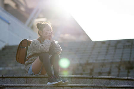 Elementary school students sitting on the steps and looking into the distanceの写真素材