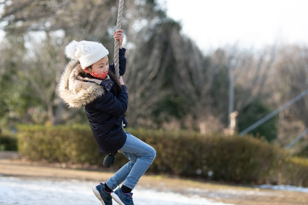 A child wearing a mask playing in a winter parkの写真素材