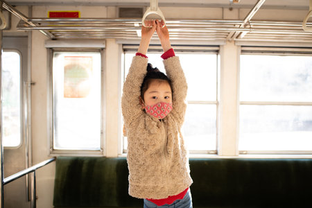Girl riding a train wearing a mask