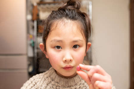 Girl eating bright red gummyの写真素材