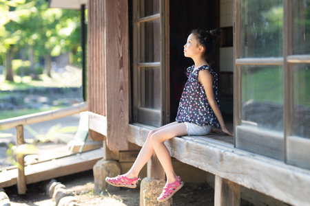 A girl sitting on the edge of a Japanese houseの写真素材