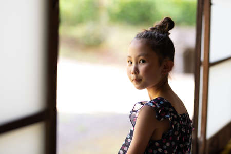 A girl sitting on the edge of a Japanese houseの写真素材