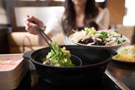A woman eating shabu shabuの写真素材