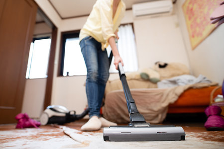 Woman cleaning the room with a vacuum cleanerの写真素材