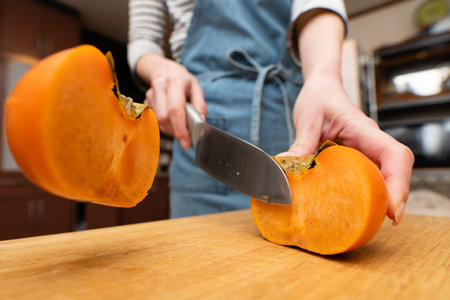 A woman's hand cutting a persimmonの写真素材