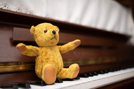 Teddy bear sitting on the piano keyboardの写真素材