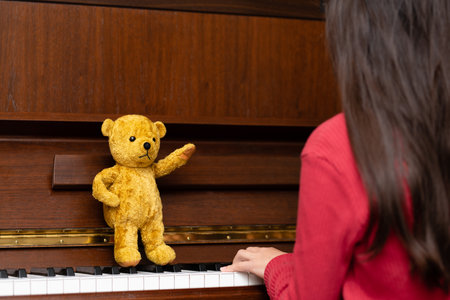 Teddy bear teaching piano to girlの写真素材