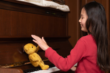 Teddy bear teaching piano to girlの写真素材