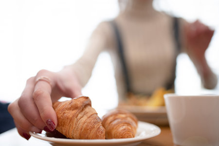 <p>Woman holding a croissant in a restaurant</p>の写真素材