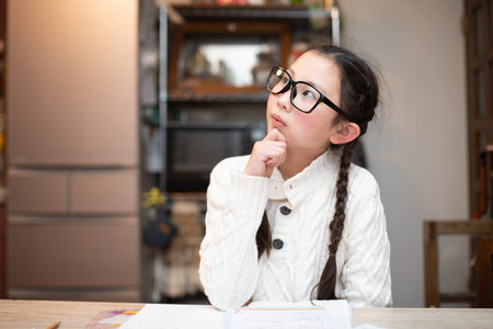 Girl wearing glasses worried while studyingの写真素材