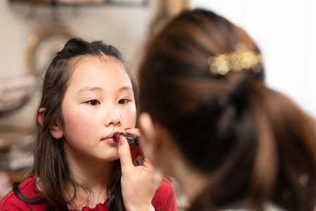 Daughter getting makeup done by motherの写真素材