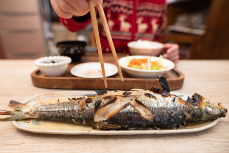 Child eating grilled fish with chopsticks