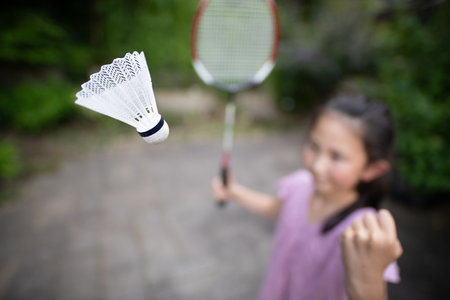 Little girl playing badminton with badminton racket and shuttlecockの写真素材