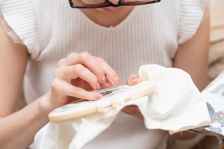 Young woman knitting at home. Close up of female hands with knitting needles.