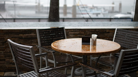 Table and chairs in an outdoor cafe on a rainy day. Selective focus.