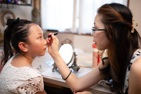 Girl learning makeup from her motherの写真素材