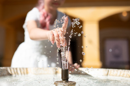 child's hand touching fountain water