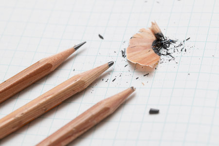 Pencils and shavings on a white sheet of paperの写真素材