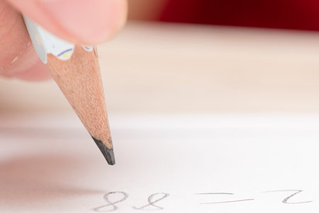 Close up of a hand writing on a white sheet of paper with a pencil