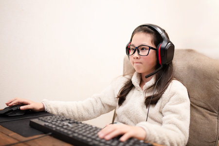 Girll in headphones sitting at a table in front of a computer