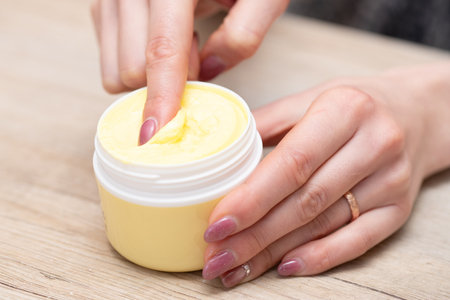 Woman's hands holding a jar of moisturizing cream on wooden backgroundの写真素材