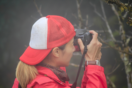 Woman wearing red shirt standing taking a photoの写真素材