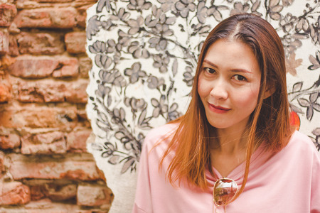 The woman stands at an old brick wall.の写真素材