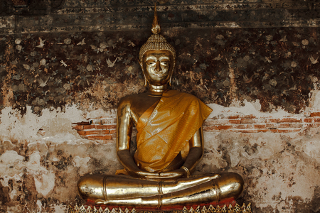 Golden Buddha beside old walls in Thai templesの写真素材