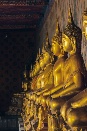 Golden Buddha statue on the pedestal with old wallsの写真素材
