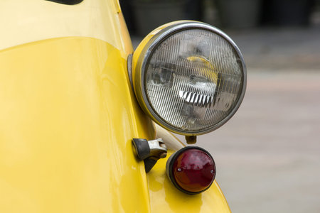 Lights in front of a vintage car with a unique sphere.