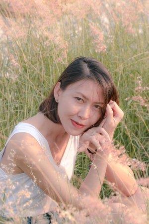 Woman sitting in the grass field With the light of the sunset
