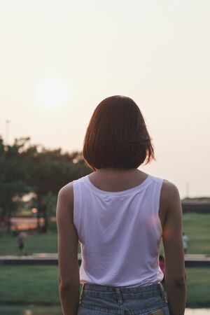 The back of the woman standing at sunsetの写真素材