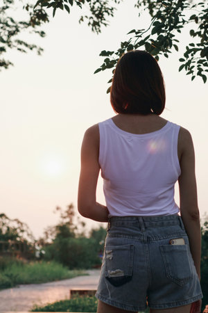 The back of the woman standing at sunset