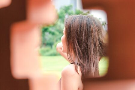 Women are turning to look through the brick wall.の写真素材