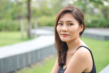 The woman sat in the park and smiled with joy.の写真素材