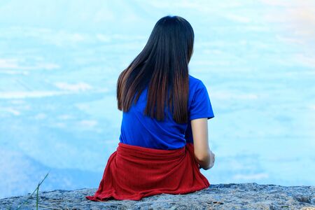 The woman was sitting back on the rock.の写真素材