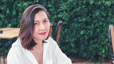 Woman sitting in a wooden chair in a restaurantの写真素材