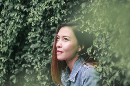 A long haired woman standing against a tree wallの写真素材