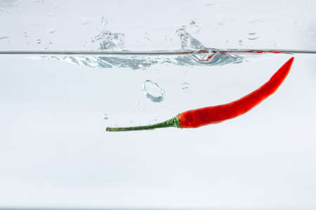 Red hot peppers fall into the splashing water.の写真素材