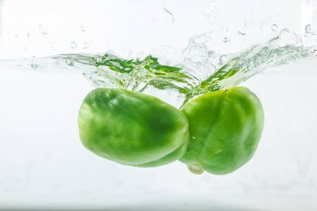 Sweet pepper in water splashes, green sweet pepper on a white background. Sweet peppers are a type of pepper. Not spicyの写真素材