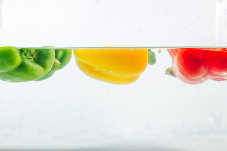 Sweet pepper in the yellow, red, green splashes of water, Sweet pepper is on a white background....