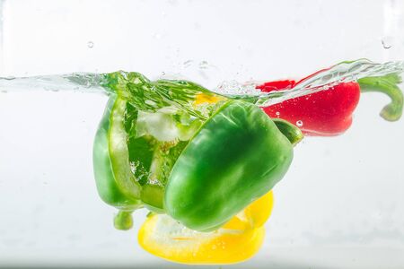 Sweet pepper in the yellow, red, green splashes of water, Sweet pepper is on a white background. Sweet peppers are a type of pepper. Not spicyの写真素材