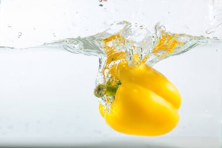 Sweet pepper in the water splashes, the yellow Sweet pepper on a white background. Sweet peppers are a type of pepper. Not spicyの写真素材