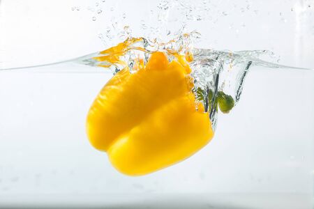 Sweet pepper in the water splashes, the yellow Sweet pepper on a white background. Sweet peppers are a type of pepper. Not spicyの写真素材
